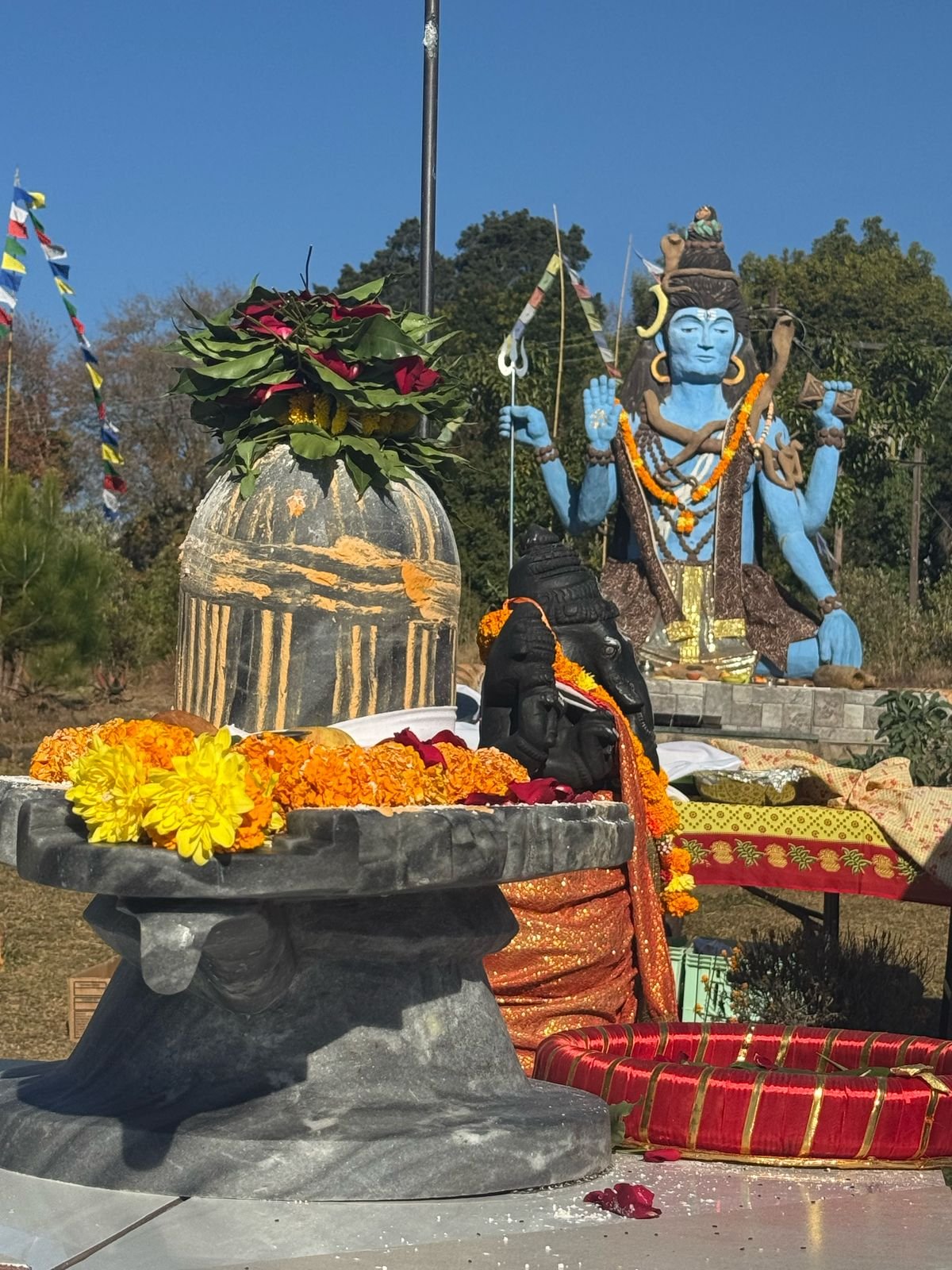Shiva lingam decorated with flowers beside the Ganesh murti and Shiva statue