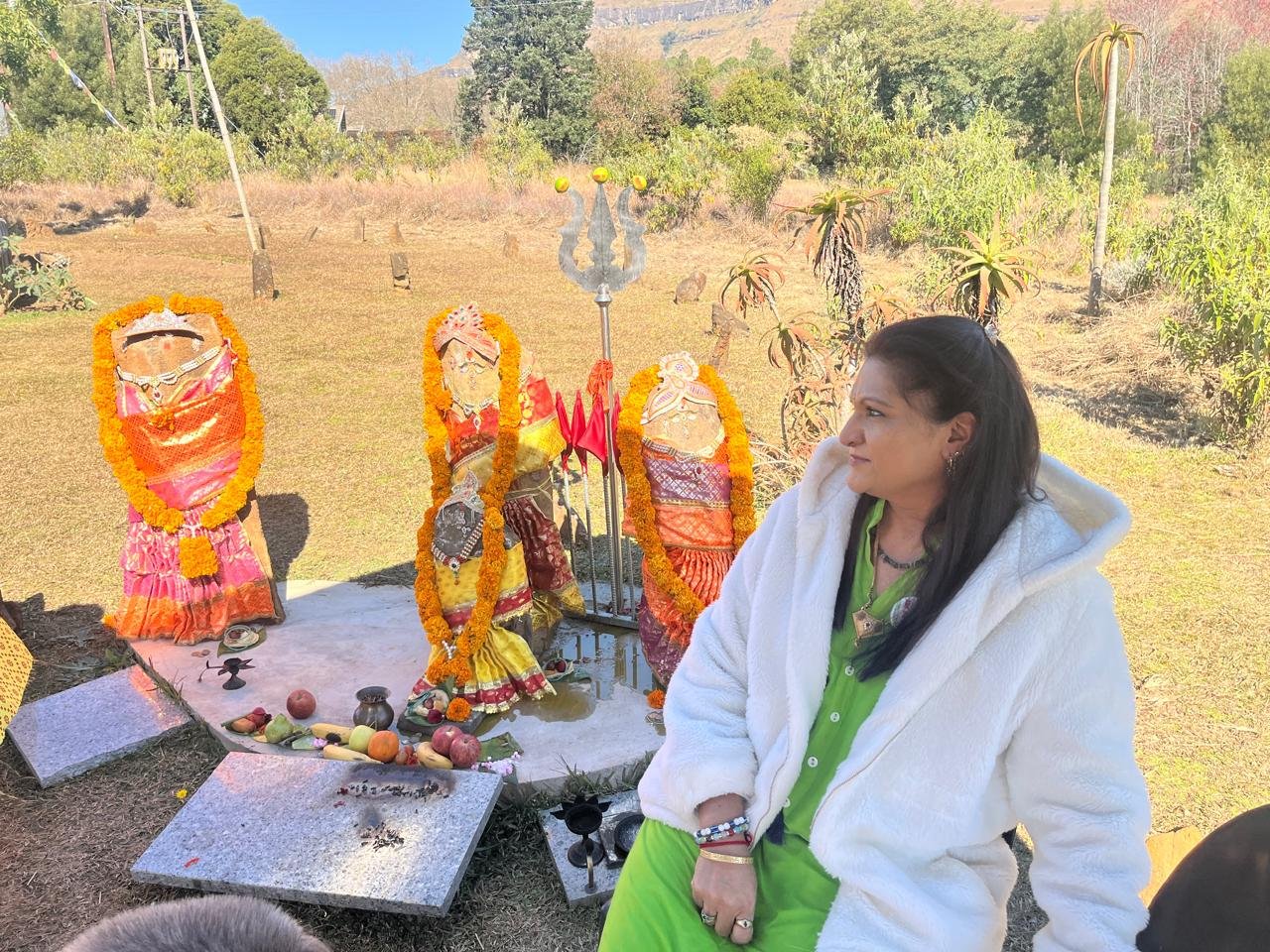 Devotee seated near draped murtis in the field